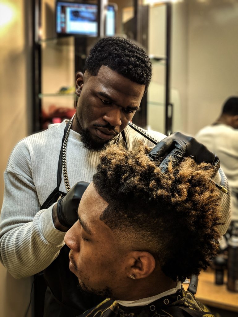 Einem Kunden werden in einem Friseursalon die Haare rasiert.